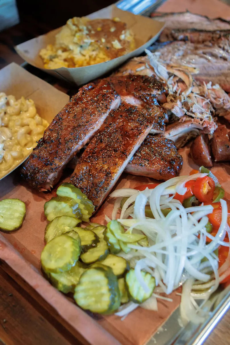 A barbecue board with ribs, pickles and onions seen from above