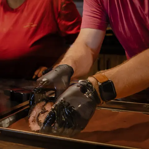 Gloved hands slicing smoked brisket