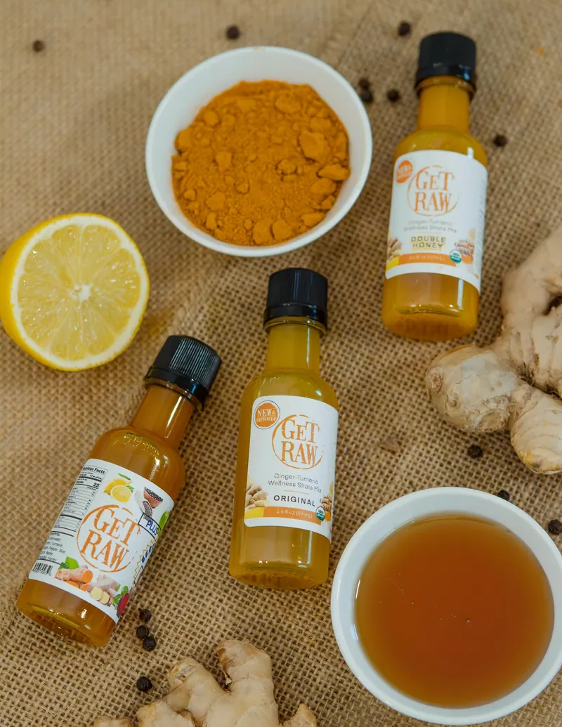 Overhead flat lay of wellness shot bottles with bowls of spices on burlap