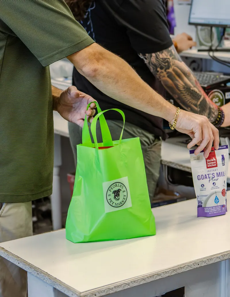 A green branded shopping bag being packed at the register