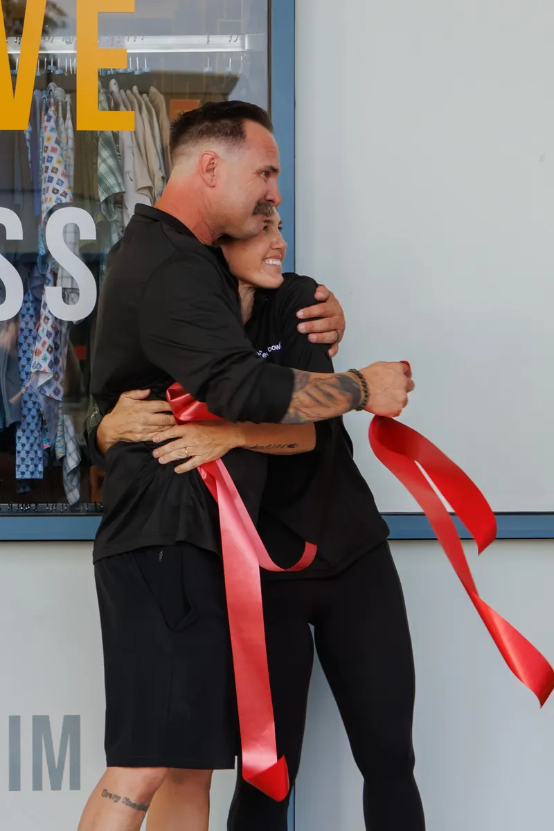 Everbowl's owners share a hug as the cut red ribbon falls away at their opening