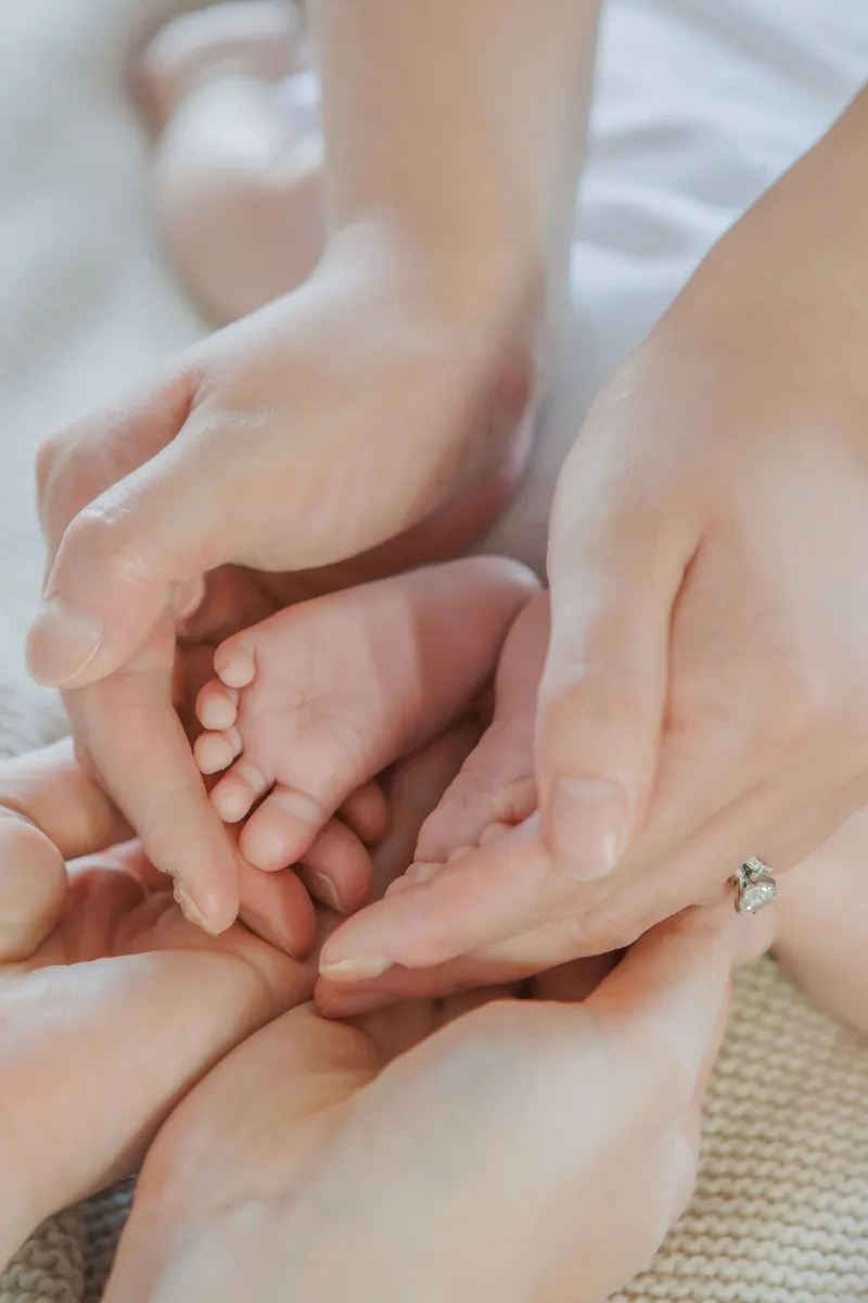 Tiny newborn feet cupped in a parent's hands