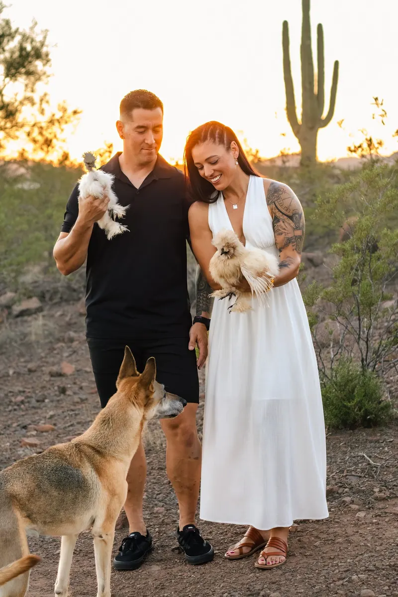 A couple poses with their German shepherd among saguaros